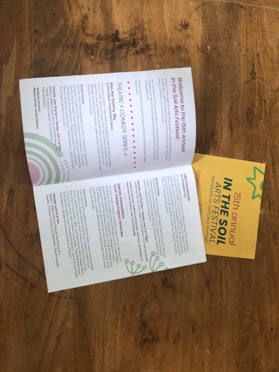 layout of a program for the In the Soil Festival on a wooden table 